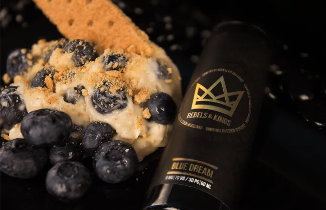 Blue Dream dessert with blueberries and a crumb topping next to a Rebels & Kings bottle