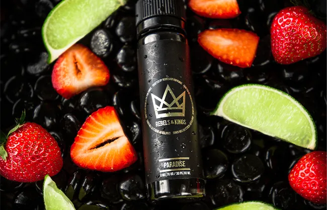 Bottle of Rebels & Kings e-liquid surrounded by fresh strawberries and lime wedges on a black background
